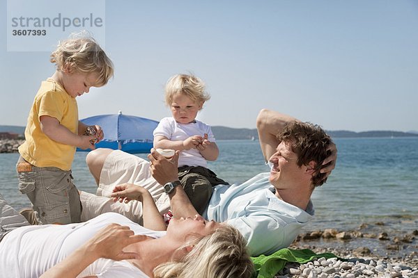 Familie am Strand mit Blick auf Muscheln