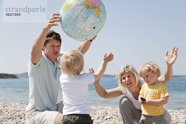 Familie mit Zwillingen am Strand beim Ballspielen