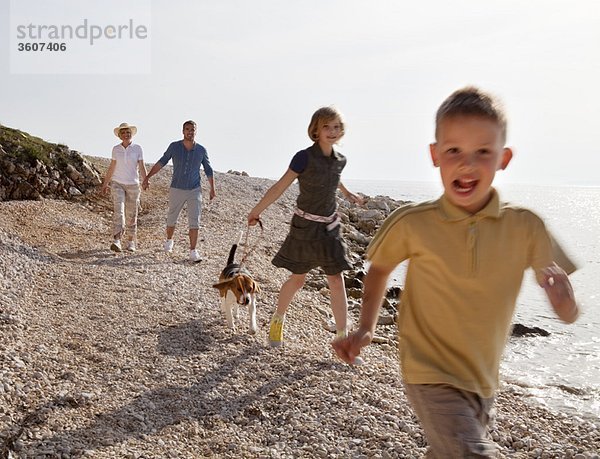 Familie mit Hund beim Laufen am Strand