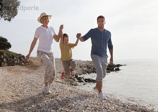 Familie mit springendem Sohn am Strand