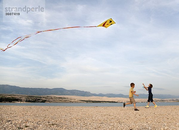 Kinder beim Drachenfliegen am Strand