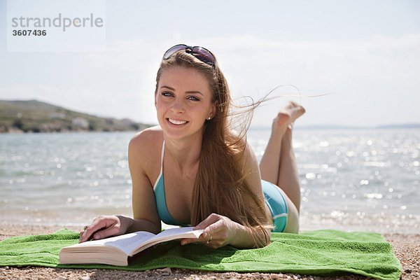 Frau beim Lesen am Strand