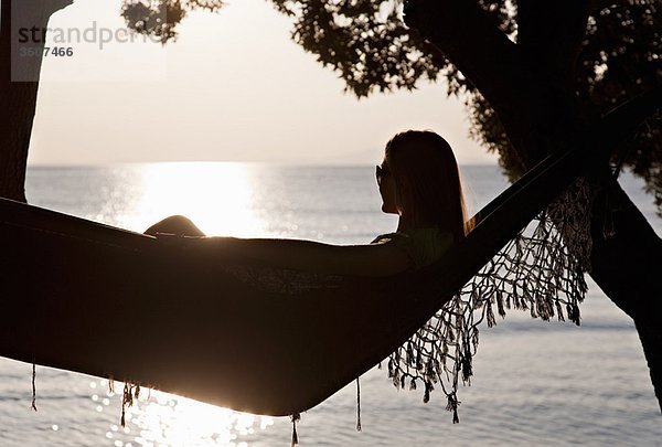 Frau in der Hängematte am Strand liegend