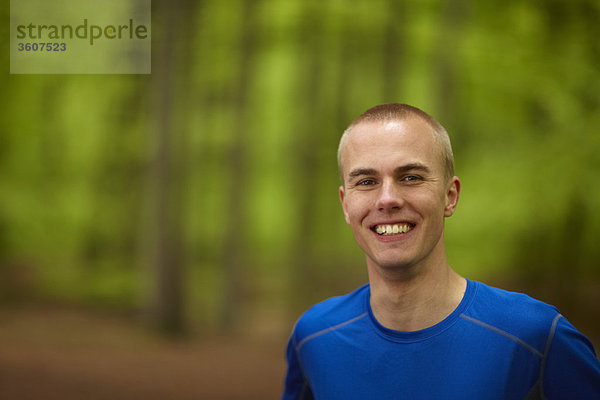 Mann läuft im Wald  Nahaufnahme  lächelnd