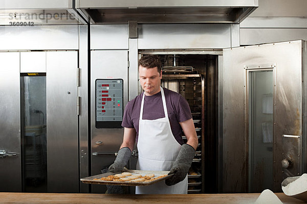 Männlicher Koch backt Kekse in der Großküche