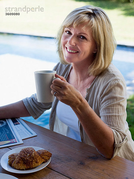 Frau im Freien mit Kaffee und Frühstück
