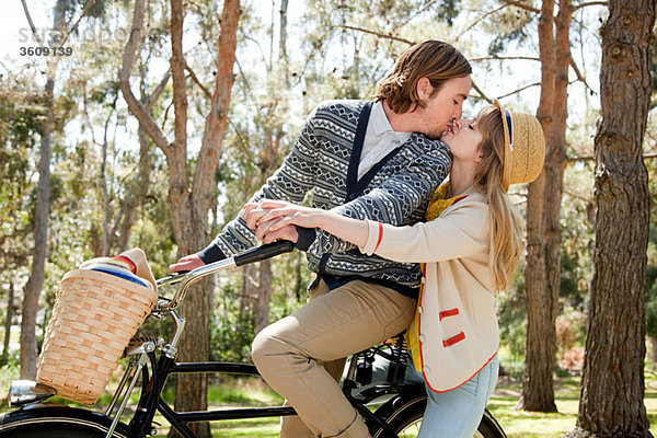 Junges Paar  das sich auf dem Fahrrad küsst