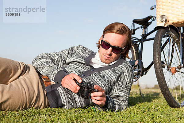 Junger Mann im Feld mit Kamera und Fahrrad