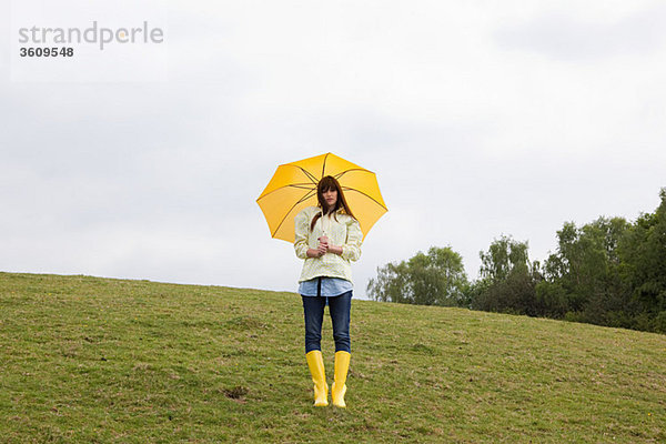 Junge Frau im Feld mit Regenschirm