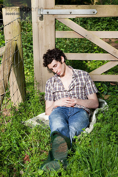 Junger Mann schläft in Landschaft