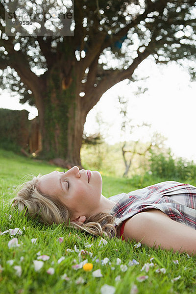 Junge Frau auf Gras liegend mit geschlossenen Augen