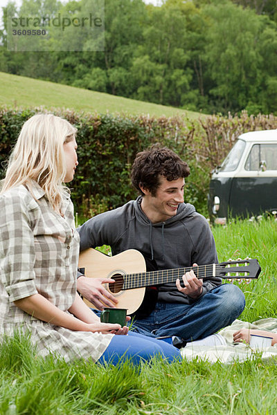 Junger Mann spielt Gitarre für Freundin