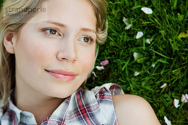 Gesicht der jungen Frau auf Gras liegend