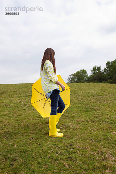 Junge Frau im Feld mit Regenschirm