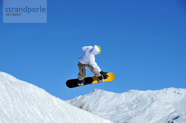 ein Snowboarder hereinkommt  während der Durchführung eines Sprunges zu landen. Alpen im Hintergrund