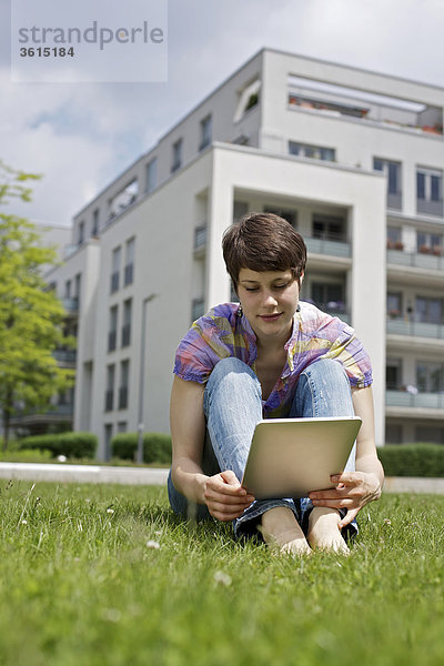 Junge Frau benutzt einen iPad im Gras