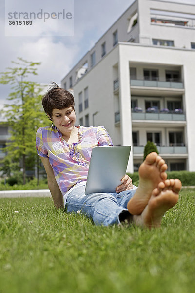 Junge Frau benutzt einen iPad im Gras