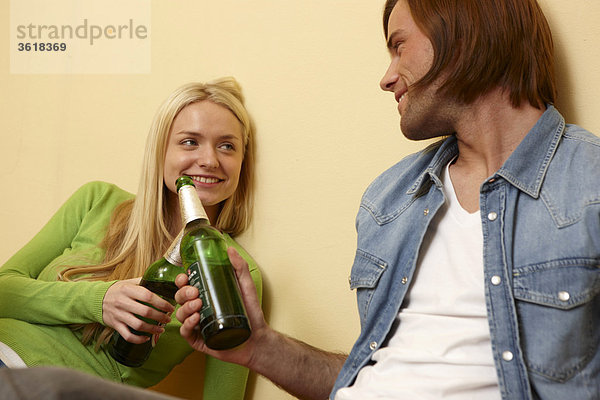 Junges Paar stößt mit Bierflaschen an