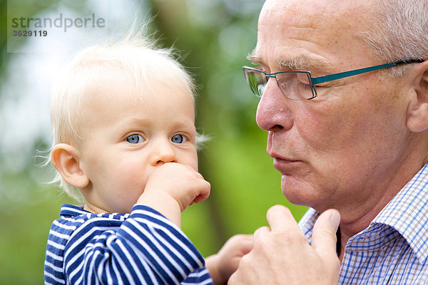 Großvater trägt Kleinkind im Freien  Portrait