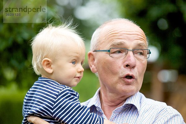 Großvater trägt Kleinkind im Freien  Portrait