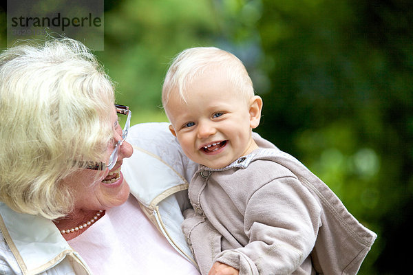 Großmutter trägt Kleinkind im Freien  Portrait