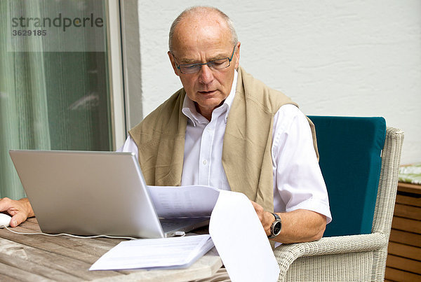 Senior benutzt Laptop auf der Terrasse