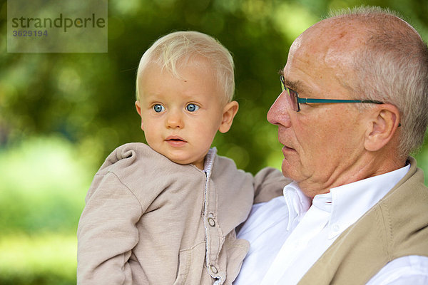 Großvater trägt Kleinkind im Freien  Portrait