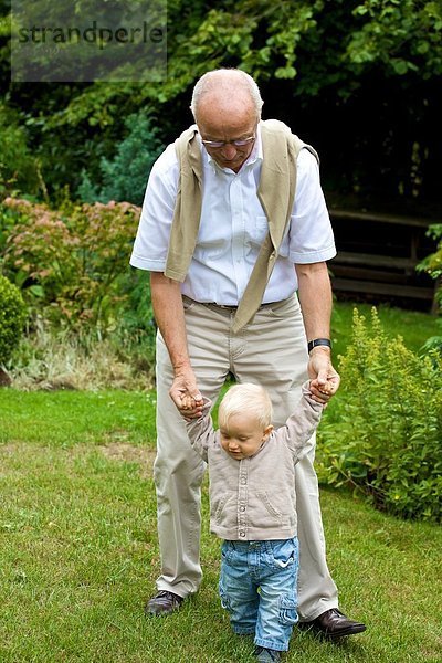Großvater hilft Kleinkind beim Gehen