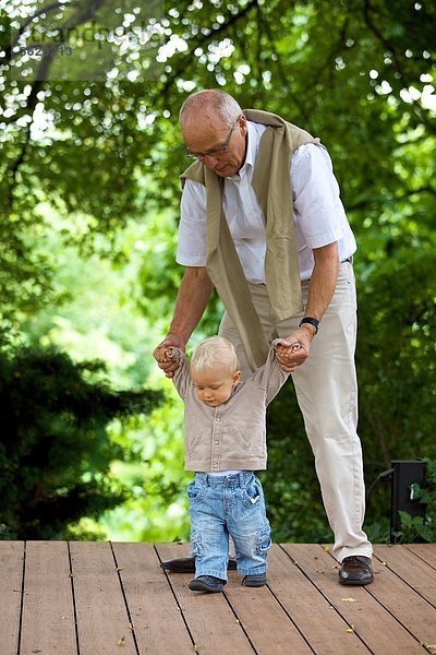 Großvater hilft Kleinkind beim Gehen