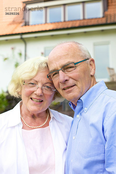 Glückliches Seniorenpaar vor Wohnhaus  Portrait