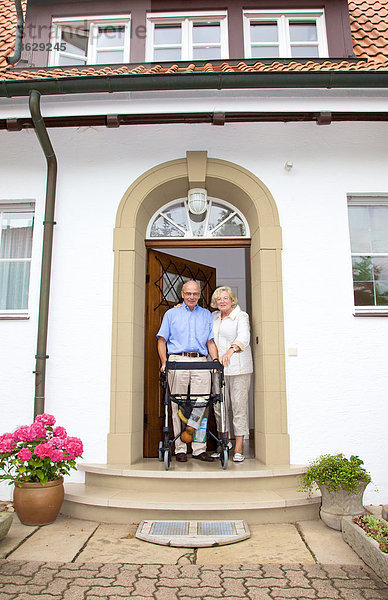 Seniorenpaar mit Rollator an der Eingangstür