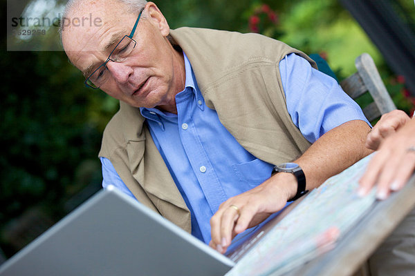 Senior mit Laptop und Straßenkarte  close-up