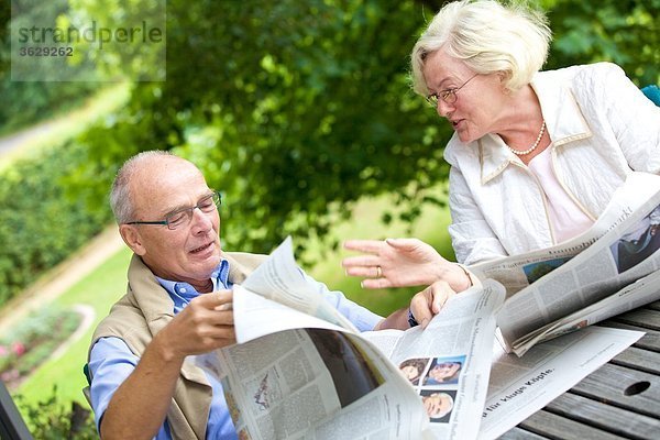 Seniorenpaar liest Zeitung auf der Terrasse