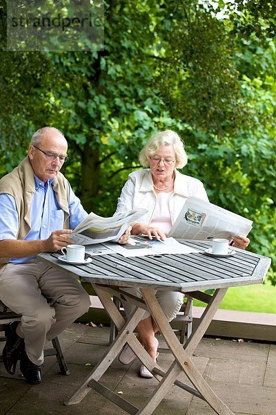 Seniorenpaar liest Zeitung auf der Terrasse