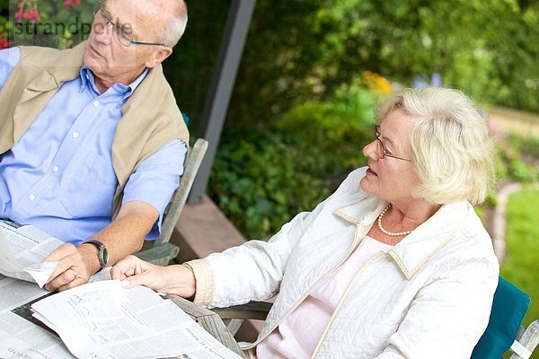 Seniorenpaar liest Zeitung auf der Terrasse