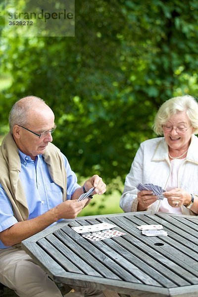 Seniorenpaar spielt Karten auf der Terrasse