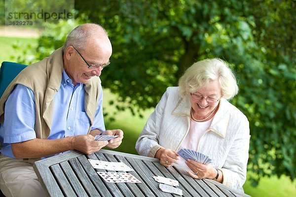 Seniorenpaar spielt Karten auf der Terrasse