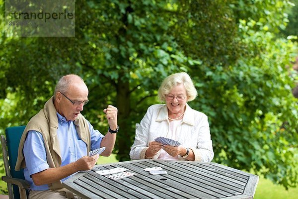 Seniorenpaar spielt Karten auf der Terrasse