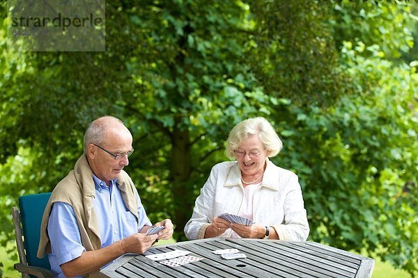 Seniorenpaar spielt Karten auf der Terrasse