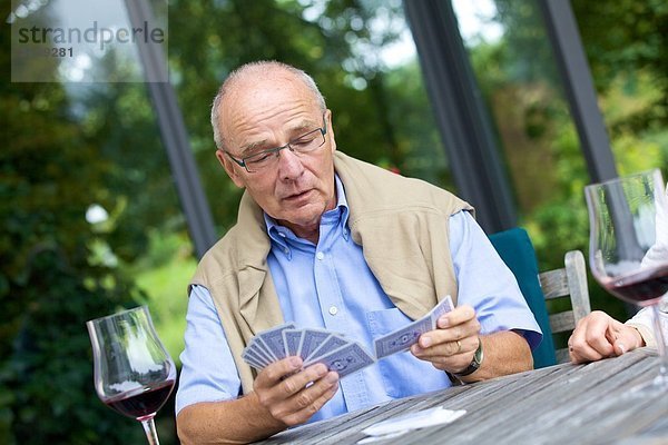 Seniorenpaar spielt Karten und trinkt Rotwein