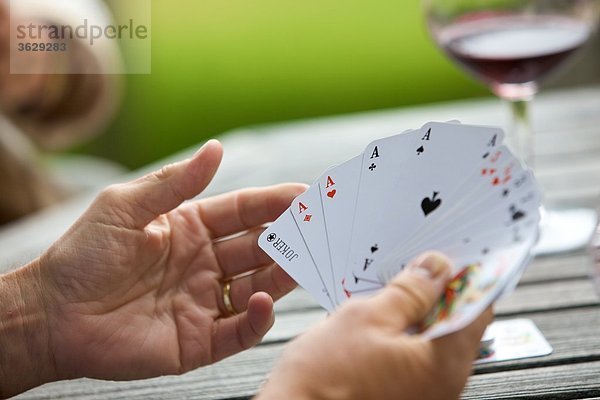 Senior spielt Karten und trinkt Rotwein  close-up