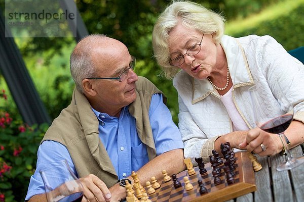 Seniorenpaar auf der Terrasse spielt Schach