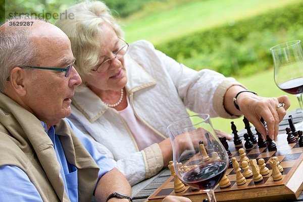 Seniorenpaar auf der Terrasse spielt Schach