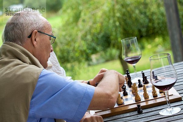 Seniorenpaar auf der Terrasse spielt Schach