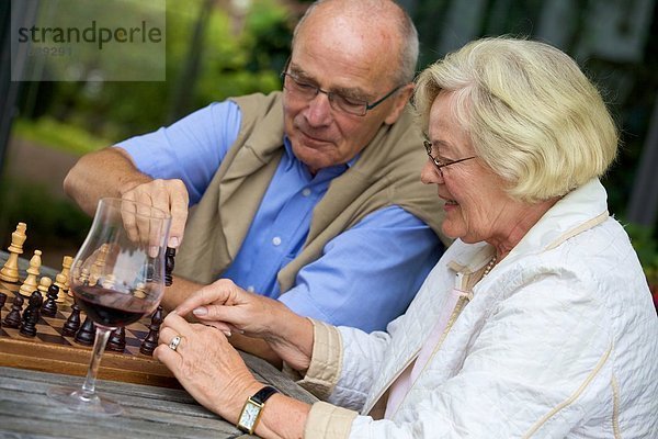 Seniorenpaar auf der Terrasse spielt Schach