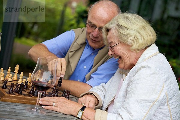 Seniorenpaar auf der Terrasse spielt Schach