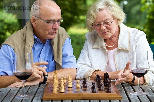 Seniorenpaar auf der Terrasse spielt Schach