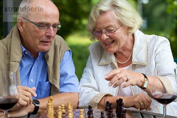 Seniorenpaar auf der Terrasse spielt Schach