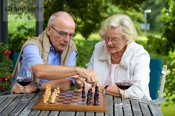 Seniorenpaar auf der Terrasse spielt Schach