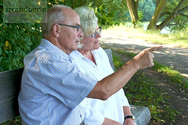 Seniorenpaar unterhält sich auf einer Parkbank